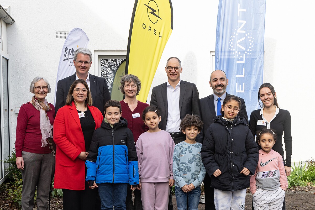 Quartiersmanagerin Berliner Viertel Arbresha Mustafa, Bürgermeister Murat Karakaya, Ralph Wangemann, Geschäftsführer Personal und Arbeitsdirektor Opel Automobile GmbH und Personalchef Stellantis in Deutschland, Elisabeth Israel, Geschäftsführerin SPV, Oberbürgermeister Patrick Burghardt, Quartiersmanagerin Berliner Viertel Samira Hammoudi, Vorsitzende der Wicherngemeinde Helen Winkler und Kinder aus dem Berliner Viertel (v.r.n.l.).